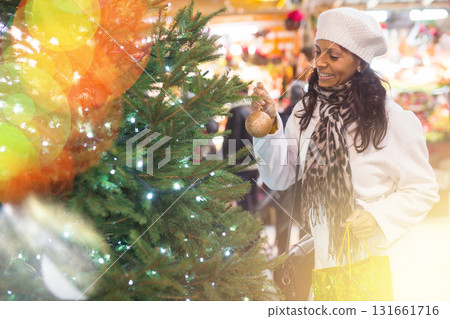 Positive hispanic woman choosing green Christmas tree at city fair Positive hispanic woman choosing green Christmas tree at city fair 131661716
