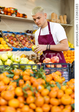 Guy shop seller puts apple goods on display case 131661883