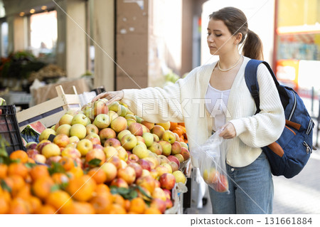 Female customer with backpack choosing yellow apples 131661884