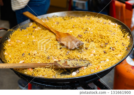 Preparation of Catalan seafood fideua in paellera on street festival Preparation of Catalan seafood fideua in paellera on street festival 131661900