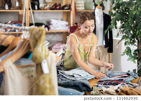 Woman shopping in clothing department, buying denim pantalones Woman shopping in clothing department, buying denim pantalones 131662030