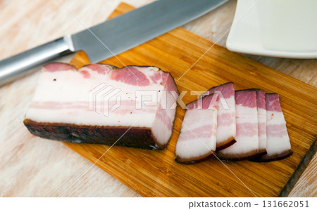 Sliced smoked pork belly on wooden cutting board with knife Sliced smoked pork belly on wooden cutting board with knife 131662051
