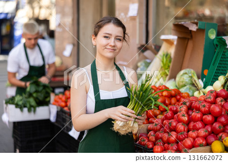 Women seller offers green onions at the market 131662072
