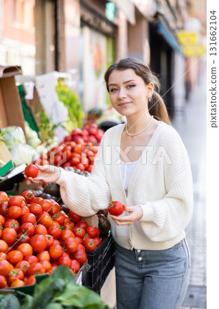 Young woman choosing red tomatoes Young woman choosing red tomatoes 131662104