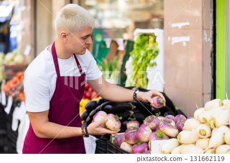 Guy shop seller puts daikon radish goods on display case 131662119