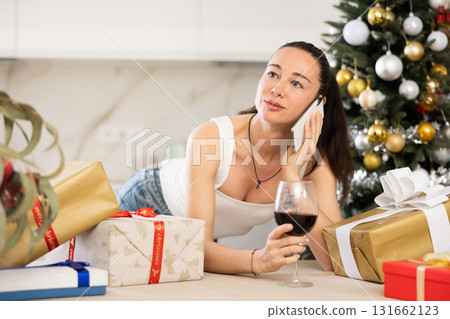 woman is relaxing at home with glass of wine during New Year holidays woman is relaxing at home with glass of wine during New Year holidays 131662123