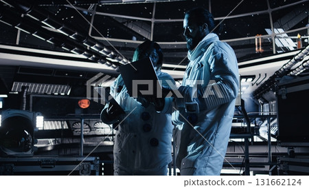 Astronaut discussing with colleague, conducting scientific experiments during space mission. Teamworking cosmonauts performing controlled tests in space during mankind survival expedition Astronaut discussing with colleague, conducting scientific experiments during space mission. Teamworking cosmonauts performing controlled tests in space during mankind survival expedition 131662124
