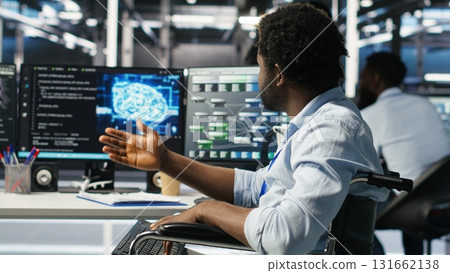 Man in wheelchair dissatisfied with server farm AI analytics metrics. Data center admin with paraplegia frustrated by glitches while automating tasks using node tree programming tool, camera B Man in wheelchair dissatisfied with server farm AI analytics metrics. Data center admin with paraplegia frustrated by glitches while automating tasks using node tree programming tool, camera B 131662138