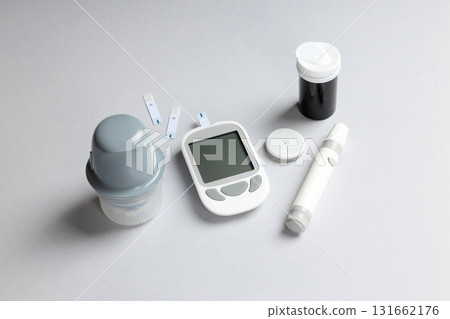 Glucose meter, strips, insulin pen, and meds arranged 131662176