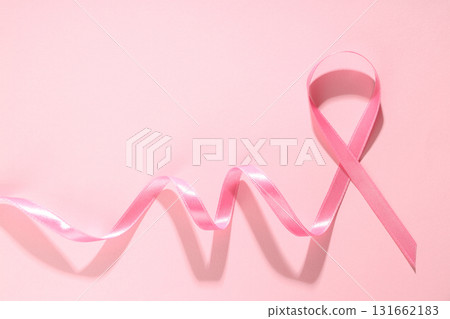 Pink ribbon laid on soft pink surface represents awareness 131662183