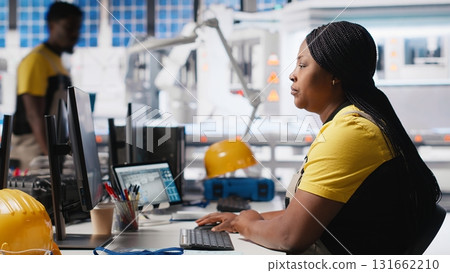 Team of black technicians finetuning the solar panels manufacturing at the plant, doing quality control for the production line. Engineers working on renewable energy industry. Camera A. 131662210