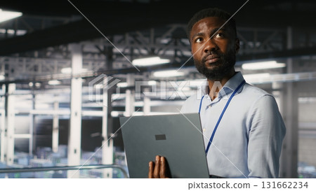 Engineers in data center using laptop to monitor neural network LLM visualization. Coworkers on server hub industrial platform overseeing server clusters powering machine learning processes Engineers in data center using laptop to monitor neural network LLM visualization. Coworkers on server hub industrial platform overseeing server clusters powering machine learning processes 131662234