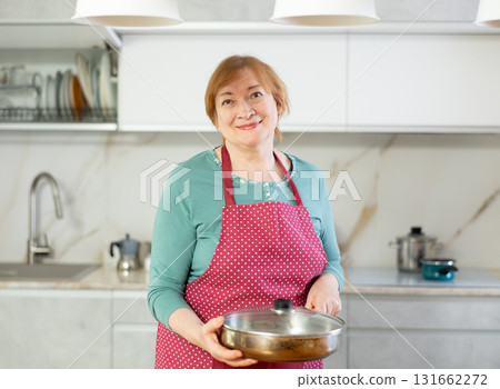 Portrait of a positive woman in an apron with a frying pan 131662272