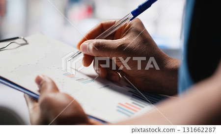 Black photovoltaics factory specialist checking configuration files, analyzing data to ensure seamless production. Solar panels manufacturing plant employee reading user manual. Camera A. 131662287