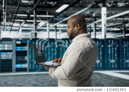 Data center engineer using artificial intelligence automation tools on laptop to increase uptime. Server hub worker working with AI machine learning to accelerate complex AI calculations Data center engineer using artificial intelligence automation tools on laptop to increase uptime. Server hub worker working with AI machine learning to accelerate complex AI calculations 131662363