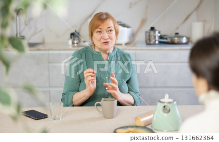 Friendly mature woman and a female guest drink tea together and talk Friendly mature woman and a female guest drink tea together and talk 131662364