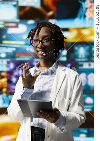 Smiling scientist using tablet to do presentation with xray scans on digital videowall. Jolly woman sharing latest neurology research to audience, using device to project pictures of human organs 131662385