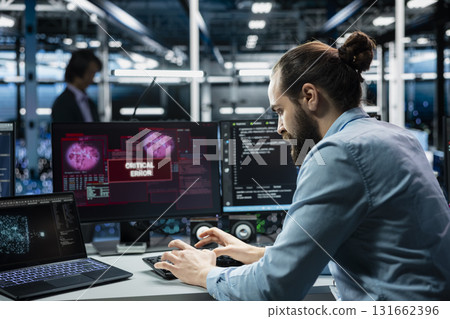 Data center programmer typing on PC keyboard, fixing error warning popup on screen using generative AI. Server hub worker using artificial intelligence chatbot to eliminate glitch alert on monitor Data center programmer typing on PC keyboard, fixing error warning popup on screen using generative AI. Server hub worker using artificial intelligence chatbot to eliminate glitch alert on monitor 131662396