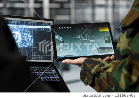 Close up of military server room engineers analyzing neural networks powered surveillance data together. Data center army specialists comparing AI generated target coordinates 131662402