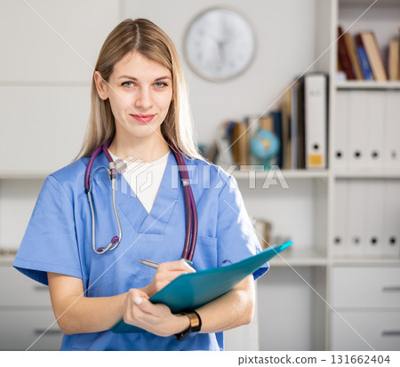 Woman doctor standing in medical office making notes 131662404