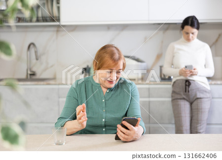 Portrait of a happy mature woman reading messages on her mobile Portrait of a happy mature woman reading messages on her mobile 131662406