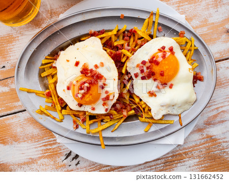 Fried eggs with french fries sprinkled with cured ham 131662452