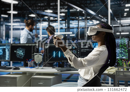 Engineer in data center using virtual reality and AI LLM assistant to do maintenance on equipment rigs. Server hub worker wearing VR headset using large language model chatbot to do backups Engineer in data center using virtual reality and AI LLM assistant to do maintenance on equipment rigs. Server hub worker wearing VR headset using large language model chatbot to do backups 131662472