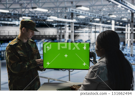 Teamworking soldiers in server hub doing brainstorming, checking reports on green screen display. Team of army information experts working together, monitoring systems using chroma key monitor 131662494