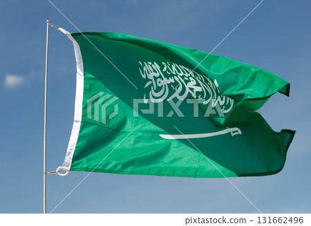 Flag of Saudi Arabia fluttering on flagpole against blue sky Flag of Saudi Arabia fluttering on flagpole against blue sky 131662496
