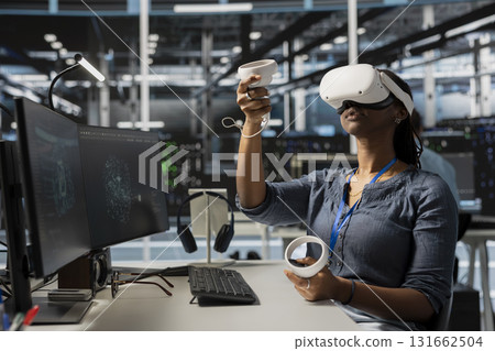 Data center worker wearing VR equipment using artificial intelligence neural networks technology. Server farm admin using virtual reality headset and AI programming language to configure hardware Data center worker wearing VR equipment using artificial intelligence neural networks technology. Server farm admin using virtual reality headset and AI programming language to configure hardware 131662504