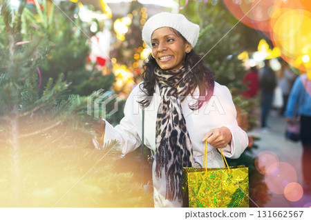 Smiling Latin American woman chooses a Christmas tree 131662567