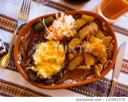 Dish of pork in Poltava with fried potatoes, pickled cabbage and cucumber 131662570