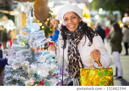 Smiling Latin American woman chooses a Christmas tree 131662594