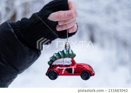 Female hands holding Christmas decoration outdoor in snowy winter forest. Postcard greeting card mock up. Holiday car toy branch Ornaments 131663042