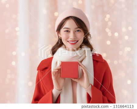 Young woman in winter attire holding a gift 131664113