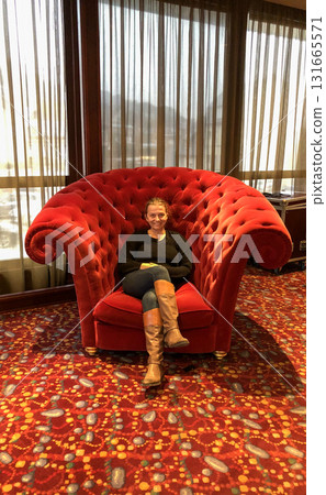 A Cozy Red Velvet Chair in a Chic Lounge Setting Providing a Comfortable Atmosphere A Cozy Red Velvet Chair in a Chic Lounge Setting Providing a Comfortable Atmosphere 131665571