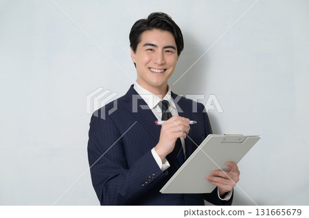 白色背景下手持剪貼簿的男人看著相機 白色背景下手持剪貼簿的男人看著相機 131665679