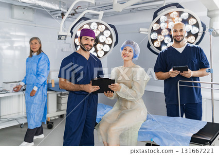 A medical team poses in an operating room, featuring surgeons and a patient, ready for a procedure. 131667221