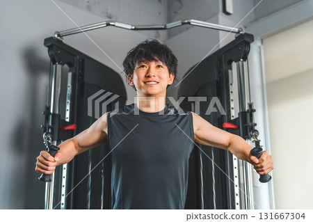 年輕的亞洲男子在健身房/訓練館使用動力架電纜進行胸肌訓練 年輕的亞洲男子在健身房/訓練館使用動力架電纜進行胸肌訓練 131667304