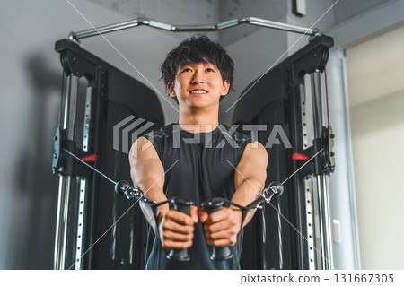 年輕的亞洲男子在健身房/訓練館使用動力架電纜進行胸肌訓練 年輕的亞洲男子在健身房/訓練館使用動力架電纜進行胸肌訓練 131667305