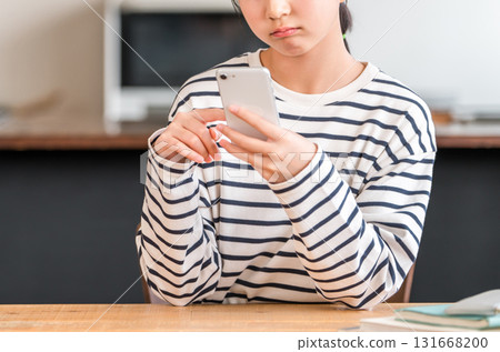 Elementary and junior high school girls using smartphones in the living room and dining room at home (depressed, troubled, worried) 131668200