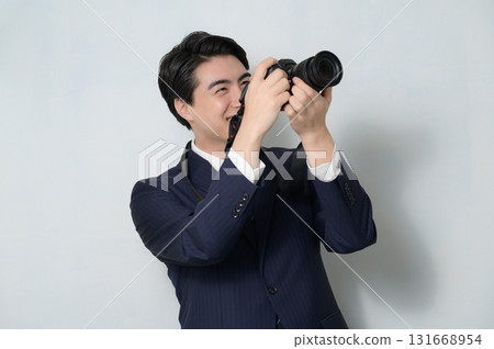 一名身穿西裝的男子拿著白色背景的相機 131668954
