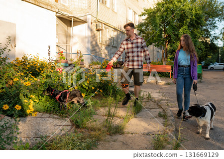 Father and daughter walking dogs past blooming flowers Father and daughter walking dogs past blooming flowers 131669129