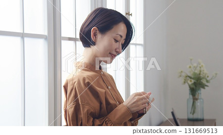 A woman listening to music or the radio by the window A woman listening to music or the radio by the window 131669513