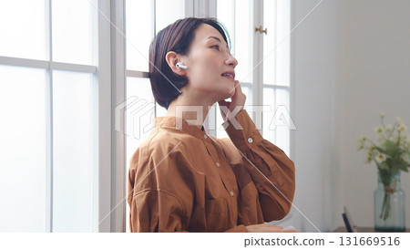 一位女士在窗邊聽音樂或聽收音機 131669516