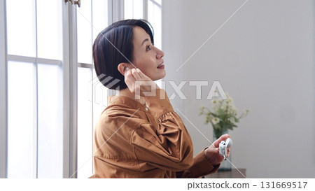 一位女士在窗邊聽音樂或聽收音機 131669517