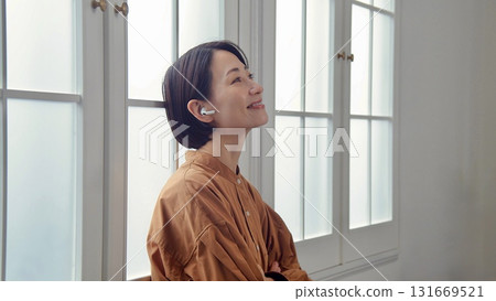 A woman listening to music or the radio by the window 131669521