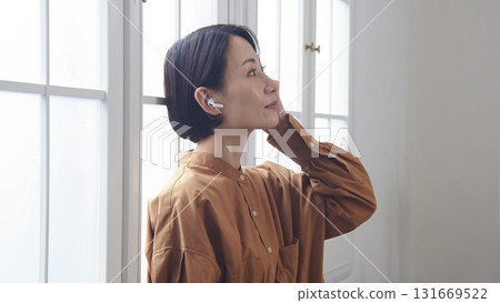 A woman listening to music or the radio by the window 131669522