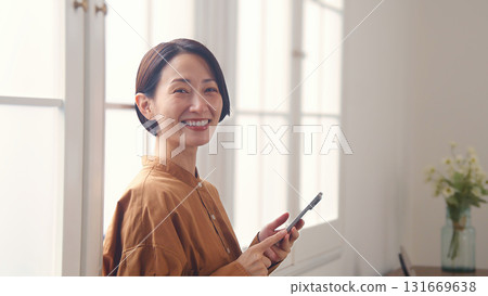 A woman using a phone by the window A woman using a phone by the window 131669638