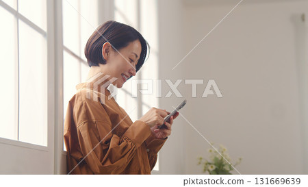 A woman using a phone by the window 131669639